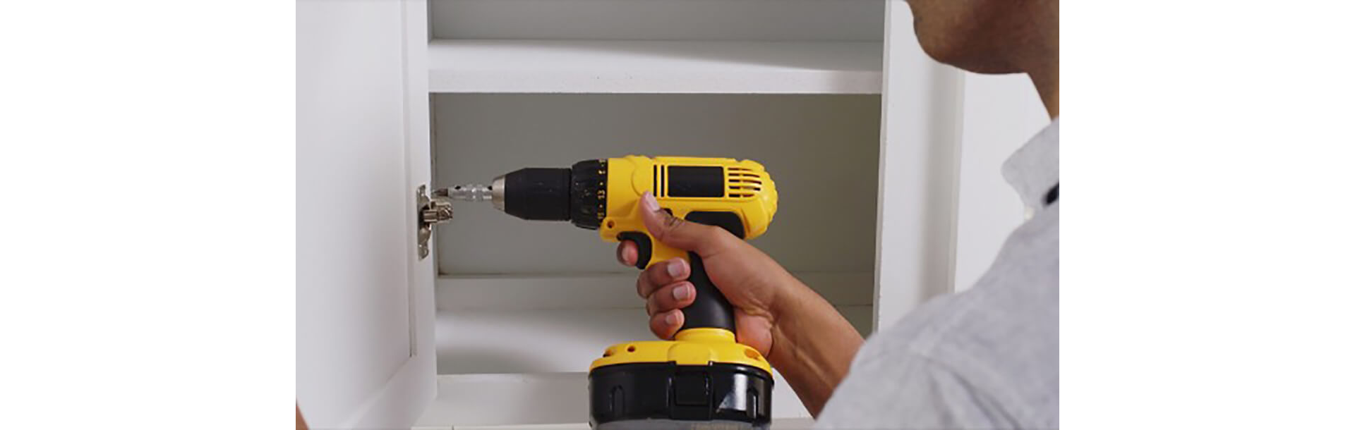 A man removing hardware from cabinets 