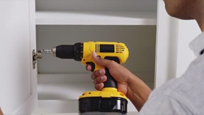 A man removing hardware from cabinets 