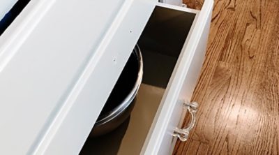 A white cabinet with hardwood floors. 