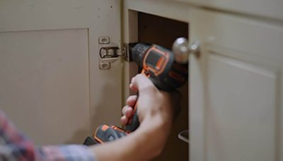A person removing cabinet doors with a drill 