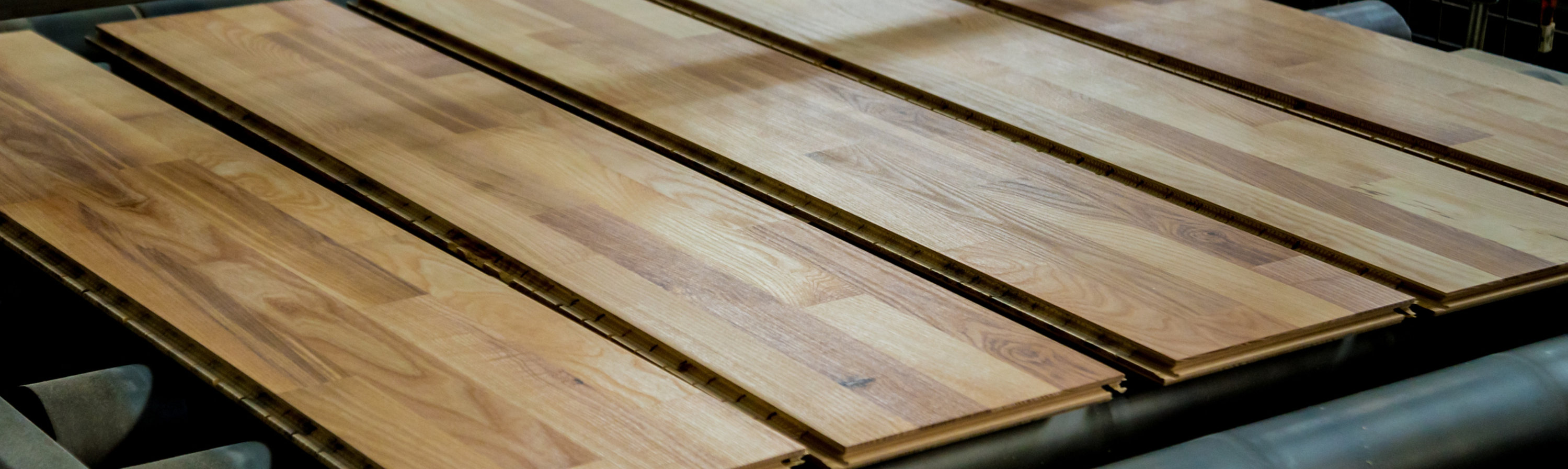 Wood flooring panels on an industrial production line, highlighting automated finishing and surface quality.