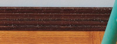 Stained wood trim with white paint splatter from a roller.