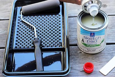 An open cannister of sketch pad paint and a black paint tray.