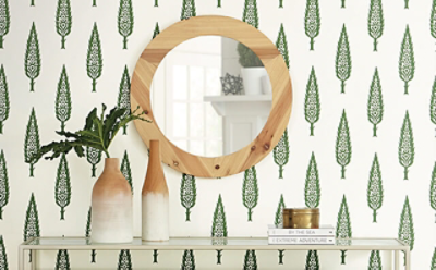 A wooden mirror on top of green patterned wallpaper.