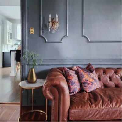 Living room painted in Roycroft Pewter with a dark leather couch, side table with plant, by @coreinteriordesign.