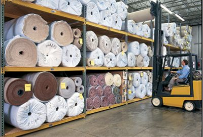 A person operating a forklift inside a Sherwin-Williams floorcovering warehouse.