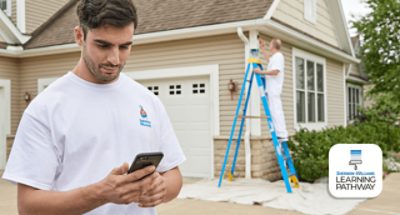 Sherwin-Williams Learning Pathway. A person standing in front of a home on his phone. A painter on a ladder painting house siding.