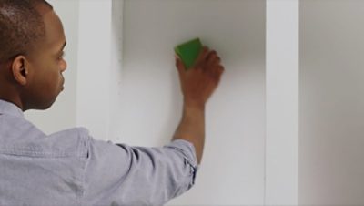 A man sanding the back panels of cabinets