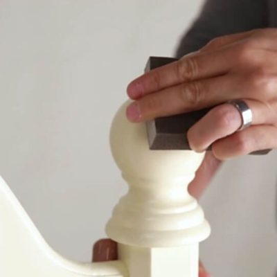 A man sanding a headboard.