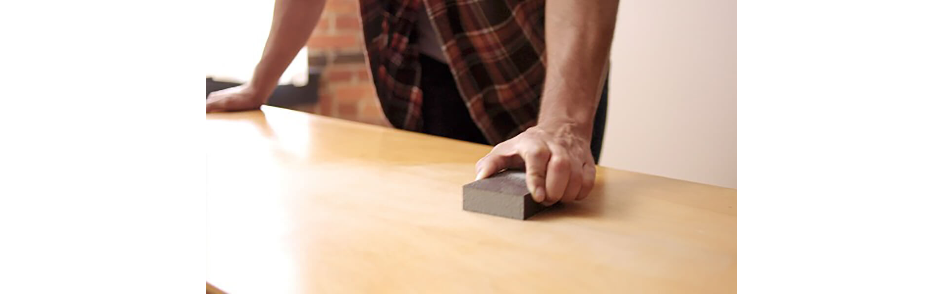 A man sanding a table surface.