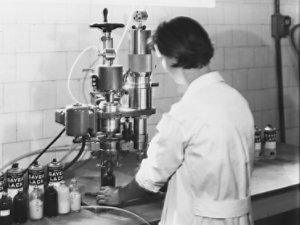 Operator in lab coat working with Sayerlack products and machinery in a clean industrial setting.