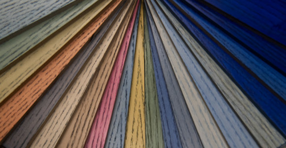 Fan-shaped display of coloured wood samples showing different finishes and tones from the CROMALIA tintometric system.