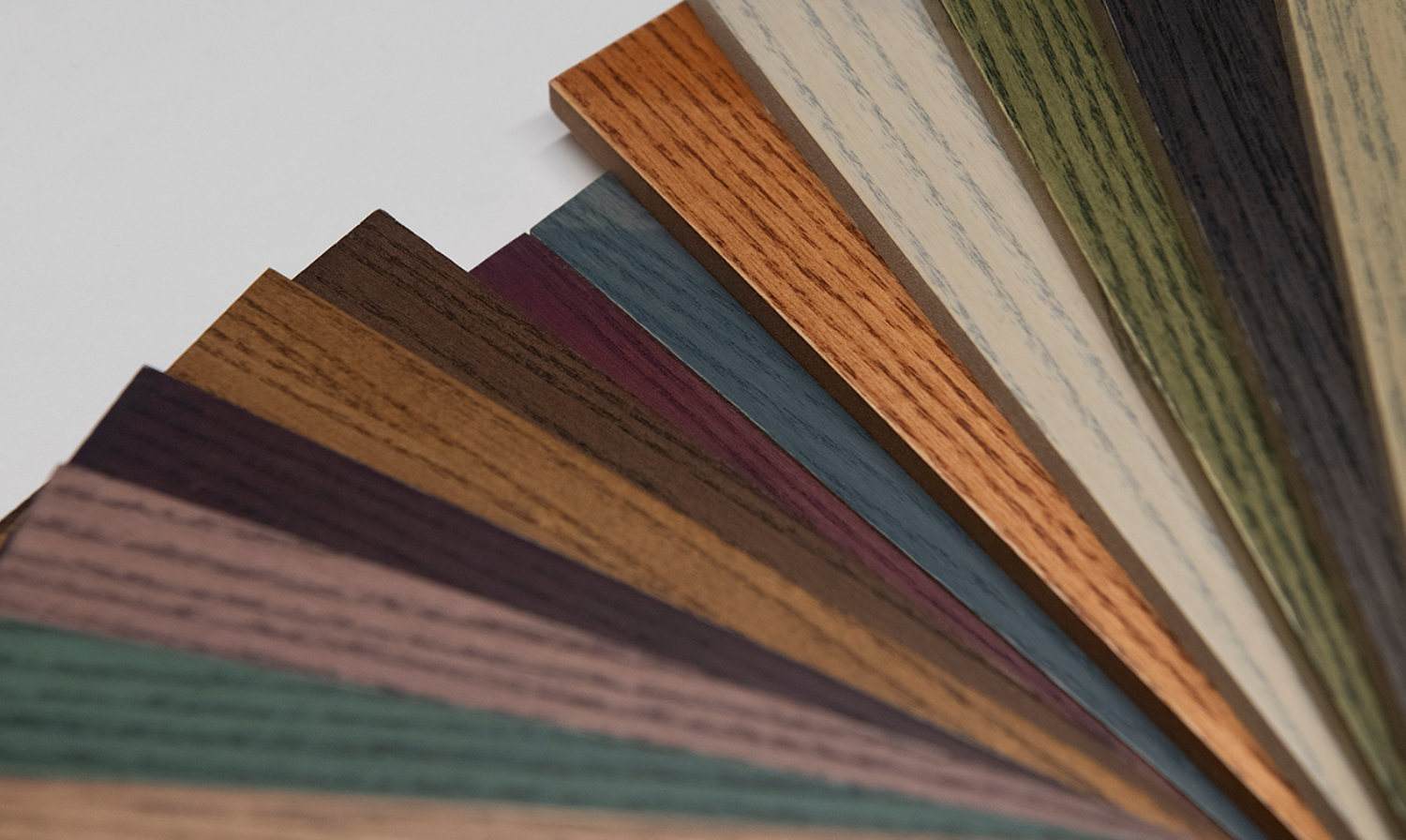 Cromalia Trends wood dyes displayed on a fan-shaped set of wood samples, highlighting a spectrum of natural and contemporary color finishes with visible wood grain.