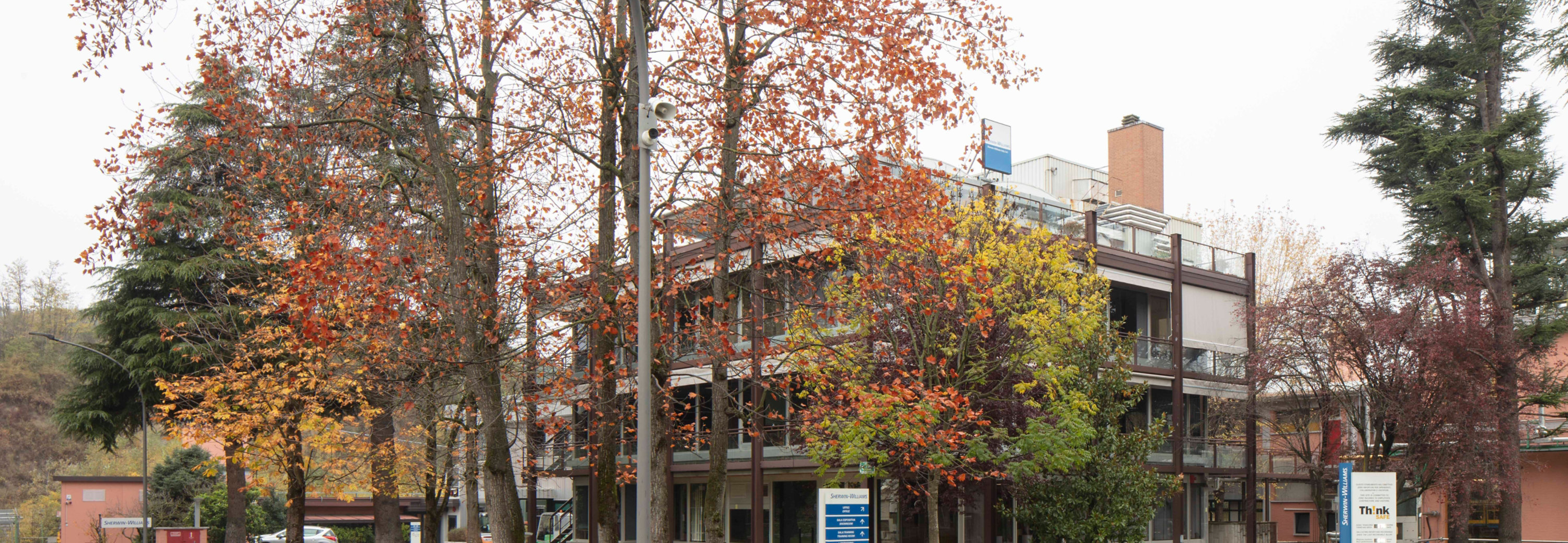 Sayerlack headquarters exterior surrounded by autumn trees, featuring modern industrial architecture and company signage.