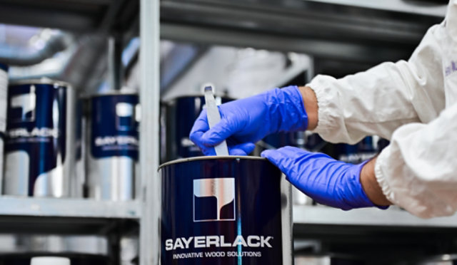 Mixing wood coating in a Sayerlack can with other containers on shelves.