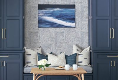 A sitting area built in between two gray-blue cabinets with wallpaper between.