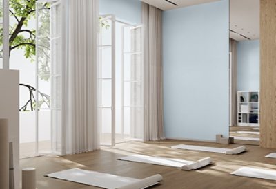 Yoga or meditation space with floor-to-ceiling open windows, Upward painted walls, and meditation mats and bolsters arranged on the natural wood floors.