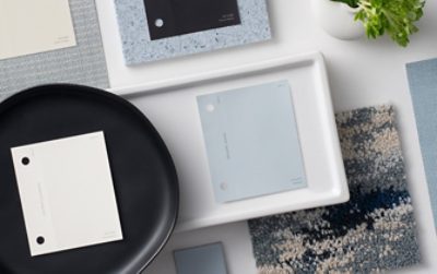 Flat lay with paint chips featuring the Sherwin-Williams Color of the Year, Upward, and its coordinating colors with flooring and wall samples, plates and trays, and other decorative elements arranged neatly.