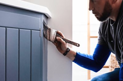  A person painting a cabinet.