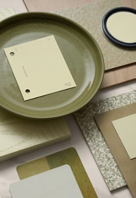 A collection of design samples including a green plate with a Celery color chip, wood panels, and various materials arranged on a marble surface.