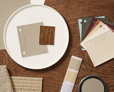 A flat lay of design materials including color swatches, fabric samples, and a wood sample of Minwax Special Walnut stain arranged on a wooden surface. 
