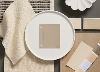 Flat lay of neutral-toned materials, featuring a Universal Khaki color swatch on a white plate, beige fabrics, tiles, and thread samples. 