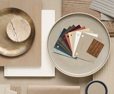 Flat lay of interior design materials including color swatches, a marble piece, brass dish, textile samples, and wood samples. 
