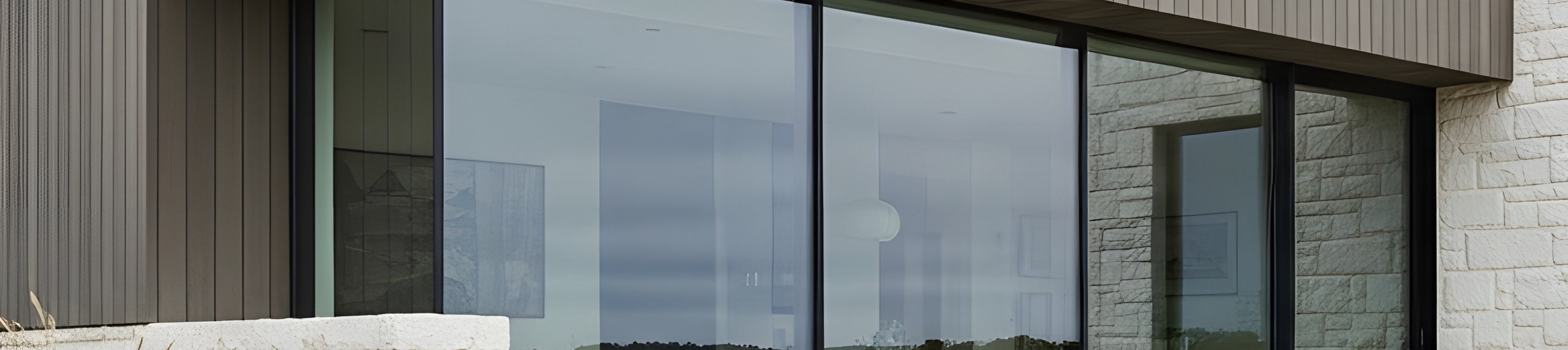 Contemporary coastal house with gray wood siding and white stone exterior, showcasing a modern design in a tranquil landscape with lush greenery, photographed from an