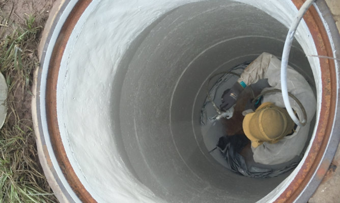 person applying coatings to rehabilitate a manhole