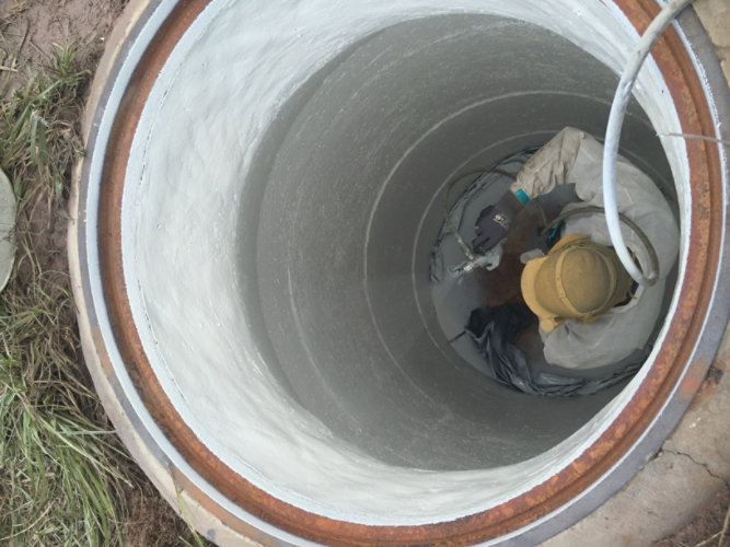 person spraying coatings to rehabilitate a manhole