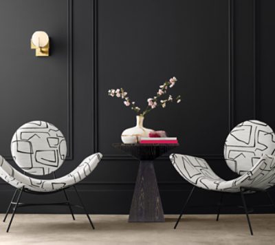 Two modern black and white chairs in front of a black wall.