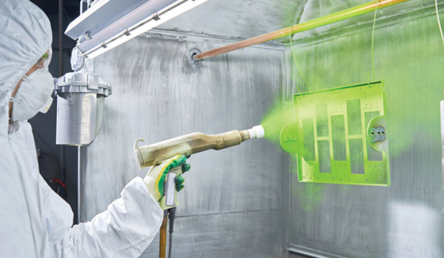 Technician spraying green powder on piece of equipment 