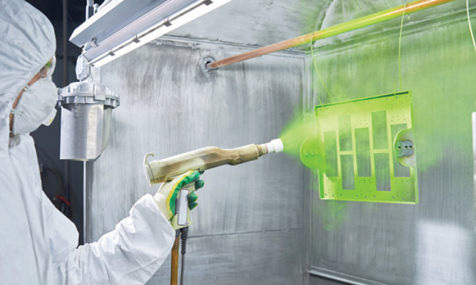 Technician spraying green powder on piece of equipment 