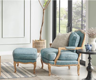 Living room with blue green chair with foot rest, small, circular black table, a large plant and French doors.