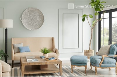 Living room with a couch, chair with foot rest, plants and French doors.