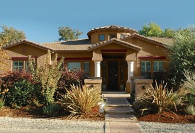 A dark tan spanish style home with red window trim and green landscaping. S-W colors featured: SW 7659, SW 6089, SW 7585