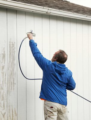 Person using a sprayer on the outside of a building.