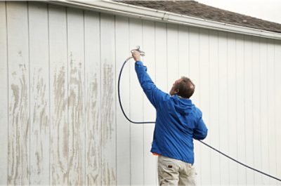 Person using a sprayer on the outside of a building.
