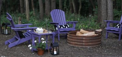 A set of purple painted chairs near a fire pit.