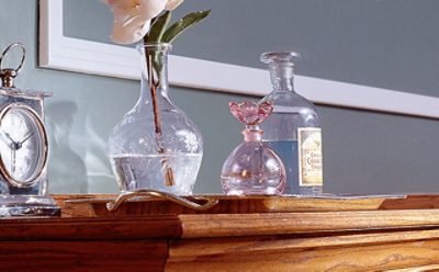 A wooden stained buffet with a glass vase. 