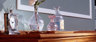 A wooden stained buffet with a glass vase.