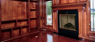 A wood stained living room with a fireplace.