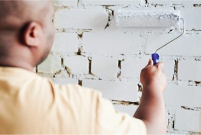Applying paint to brick with a roller.
