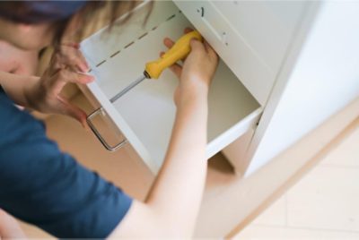 A person removing cabinet hardware.