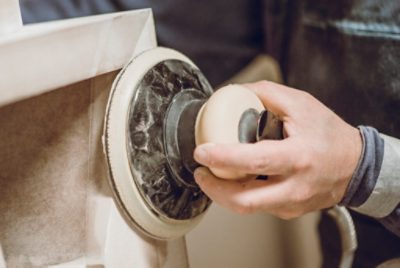 A person sanding a cabinet.
