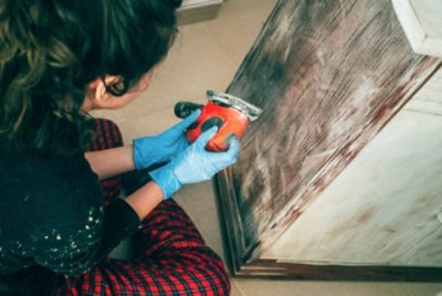 A person using a sander on a cabinet.