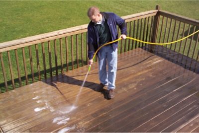 A man power washing a deck.