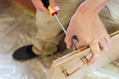 Person prepping wood for staining.