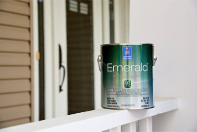A can of Sherwin-Williams Emerald paint on a front porch.