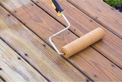 Deck stain being applied with a roller.
